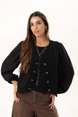 Chaleco negro con escote en V y cierre frontal mediante botones. Presenta un diseño versátil y moderno, ideal para usar solo o como capa sobre otras prendas.