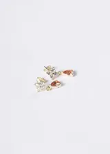 Par de aros colgantes de plata 925 con baño de oro de 18k, compuestos por un diseño superior de cuatro zirconias blancas en forma de flor y un dije colgante en forma de gota de zirconia color anaranjado.