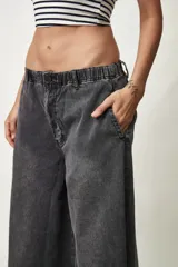 Jean de corte ancho y silueta oversize, color gris oscuro con efecto acid wash. Presenta pretina elástica y ruedo desmechado.