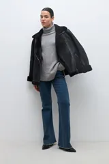 Sweater gris melange de tejido buclé con cuello alto y mangas largas.