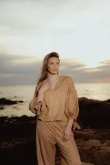 Blusa color ocre con estampado de flores, escote en V, mangas largas abullonadas con lazo en los puños y corte holgado.