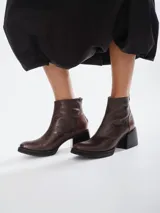 Botinetas de cuero vacuno con textura tipo reptil en color marrón chocolate. Presentan un diseño de caña media con cierre posterior, puntera redondeada y suela de goma con taco cuadrado robusto.