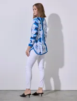 Buzo tejido en hilado fino, con cuello redondo y mangas 3/4. Presenta un estampado floral en tonos azules sobre un fondo a rayas verticales en diferentes tonos de azul.