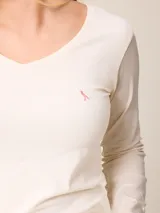 Remera de manga larga color gris, con cuello en V y logo bordado de un pájaro en el pecho.