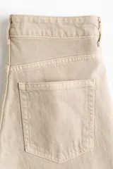 Jean de tiro alto y piernas amplias confeccionado en denim de algodón con diseño de cinco bolsillos y cierre frontal con botón y cremallera.