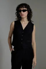 Chaleco negro de corte sastrero con escote en V y cierre frontal con botones.