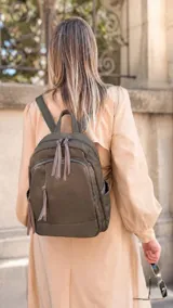 Mochila de diseño funcional confeccionada en tafeta, color verde oliva. Cuenta con compartimento principal con cierre, dos bolsillos frontales con cierres metálicos, bolsillos laterales y un bolsillo adicional en el dorso. Incluye correas regulables y tiradores de cierre en cuero sintético.