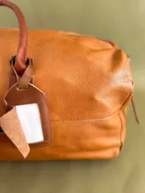 Tag identificatorio para bolsos y mochilas de cuero tostado con ventana para datos y solapa de cierre.