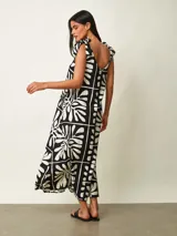 Vestido midi negro con estampado gráfico en blanco, de corte amplio y escote redondo con tirantes anudados en los hombros.