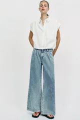 Jeans de tiro medio con pernera ancha, diseño wide leg y pinzas delanteras. Cuenta con bolsillos frontales, bolsillos traseros de plastrón y cierre frontal con cremallera y botón.