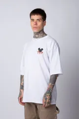 Remera negra de algodón de corte oversize, con mangas cortas y cuello redondo. Estampado pequeño en el frente y diseño grande en la espalda con Mickey Mouse y caracteres orientales en tonos rojizos.