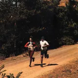 Championes de trail running Salomon DRX Defy Grvl, color negro con detalles en naranja y entresuela verde menta, diseñados con soporte y ligereza para correr en caminos de grava y asfalto.