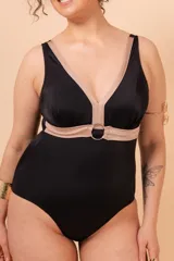 Malla entera de natación color negro con detalles en color beige. Presenta escote en V profundo con tirantes anchos y un falso cinto bajo el busto que se une con una argolla metálica central.