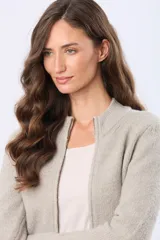 Campera tejida de punto con cierre frontal completo, cuello tipo mao y puños acanalados. Presenta un parche decorativo de cuero sintético en la parte inferior y un diseño de textura suave y abrigada.