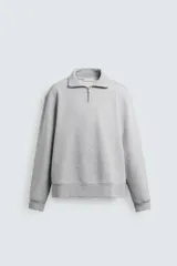 Sudadera de color gris melange, corte regular fit, con cuello alto y cierre frontal de cremallera. Presenta mangas largas y acabados en rib en puños y bajo.
