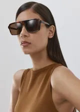 Top de punto fino color tostado, sin mangas, con cuello redondo y diseño recto que incluye una tira integrada para anudar en la cintura.