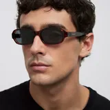 Lentes de sol con montura de diseño rectangular y bordes redondeados en estampado carey marrón, con cristales polarizados en color negro.