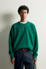 Sudadera de corte regular fit en color verde, con cuello redondo, manga larga raglán y acabados en rib elástico en cuello, puños y dobladillo.