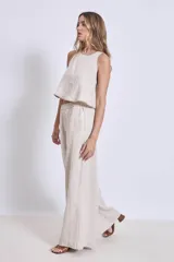 Pantalón de lino color beige, de corte amplio y tiro alto, con cintura elástica y bolsillos laterales.