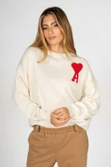 Sweater color crudo de corte holgado con cuello redondo y logo de corazón rojo bordado en el pecho.