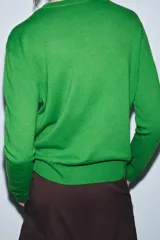 Jersey de punto liso color verde, con cuello redondo y manga larga. Confeccionado en lana suave.