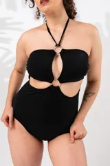 Malla entera negra con escote strapless, breteles finos al cuello y espalda recta. Presenta aberturas en el abdomen unidas por aros metálicos.