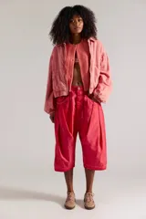 Pantalón harem de tiro caído, color rojo con efecto lavado, diseño de silueta globo con tablas al frente, bolsillos amplios y largo por debajo de la rodilla.