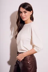 Remera de algodón color blanco roto, con escote redondo y mangas globo de tres cuartos con elástico en el puño.