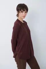 Cardigan de punto color beige, con cuello camisero, cierre frontal de botones y bolsillo aplicado en el pecho. Presenta mangas largas con puños acanalados y un corte recto y holgado.