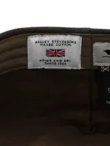 Boina de estilo clásico confeccionada en canvas engrasado impermeable con diseño a cuadros oscuros. Cuenta con forro interior de algodón orgánico.