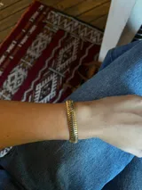 Pulsera dorada ancha con eslabones rectangulares.