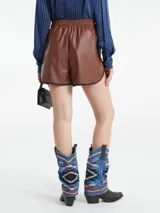 Short negro de cuerina con elástico en la cintura y vivos grises en el ruedo.