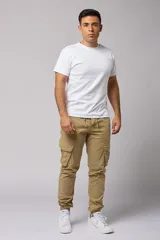 Pantalón cargo color beige de gabardina, con corte ajustado, bolsillos laterales con fuelle y puños elásticos en los tobillos.
