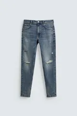 Pantalón jean skinny fit de color azul con efecto lavado y roturas sutiles en las piernas, de tiro medio y corte ajustado.