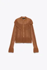 Chaqueta de punto pointelle color tostado, con cuello subido y manga larga. Presenta detalles de volantes en el pecho y puños, y cierre frontal con botones.