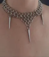 Collar plateado con eslabones circulares y tres dijes colgantes en forma de cono.