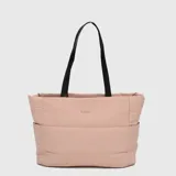 Bolso tipo tote acolchado de color rosado, con diseño minimalista y logo frontal. Cuenta con correas largas de color negro para llevar al hombro y bolsillos laterales. Incluye compartimento interno para laptop y sistema de sujeción para maletas.