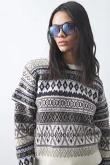 Sweater de punto con diseño jacquard de inspiración nórdica, cuello redondo y mangas largas. Presenta un patrón geométrico en tonos tierra, azul y blanco, con puños y ruedo acanalados.