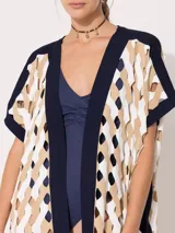 Poncho verde esmeralda con paneles estampados en tonos rosa y beige, cuello en V y mangas cortas.