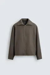 Sobrecamisa relaxed fit color marrón grisáceo, confeccionada en tejido de sarga con estructura diagonal. Cuenta con cuello subido, manga larga, bolsillos de vivo en la cadera y cierre frontal con cremallera.