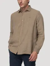 Camisa de manga larga de lino color tostado de la marca RKF, con cierre frontal de botones y cuello camisero clásico. Presenta un pequeño logo bordado en el pecho.
