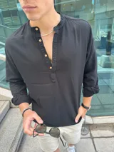 Camisa de cuello mao en color negro, confeccionada en tejido símil lino. Presenta mangas largas con puños arremangados y una abertura frontal con botones de madera.