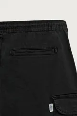 Bermuda cargo color negro de corte relaxed fit, confeccionada en tejido de algodón con elasticidad y efecto lavado. Cuenta con cintura elástica ajustable con cordón, bolsillos frontales y bolsillos laterales tipo cargo con solapa en las perneras.