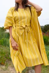 Vestido túnica amarillo con rayas verticales blancas, corte amplio, mangas cortas y lazo para ajustar en la cintura.