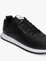 Zapatillas deportivas Tommy Hilfiger de estilo running, confeccionadas en una mezcla de piel y poliuretano. Presentan un diseño de corte bajo con cordones, paneles de texturas mixtas, detalles de ventilación en la parte superior y suela de goma con tacos.