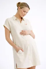 Camisa maternal de corte holgado y largo midi, confeccionada en viscosa suave con estampado geométrico de cuadros en color verde agua y blanco. Presenta cuello camisero, mangas cortas y bolsillos laterales.