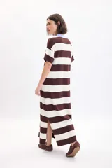Vestido largo de punto a rayas horizontales en color marrón y beige, con mangas cortas y cuello polo celeste con botones negros.