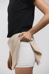 Pollera deportiva de corte acampanado color beige, con calza corta integrada de color blanco. Presenta cintura ancha de tiro alto y bolsillo invertido en la calza para guardar pelotas.