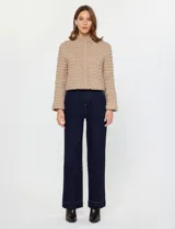 Campera de mujer color azul marino, con textura capitoneada de efecto burbuja o nido de abeja. Presenta cuello alto con cierre frontal y corte recto y corto.