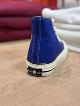 Zapatillas de lona color beige, tipo bota, con cordones marrones, puntera de goma y logo de peach engomado.